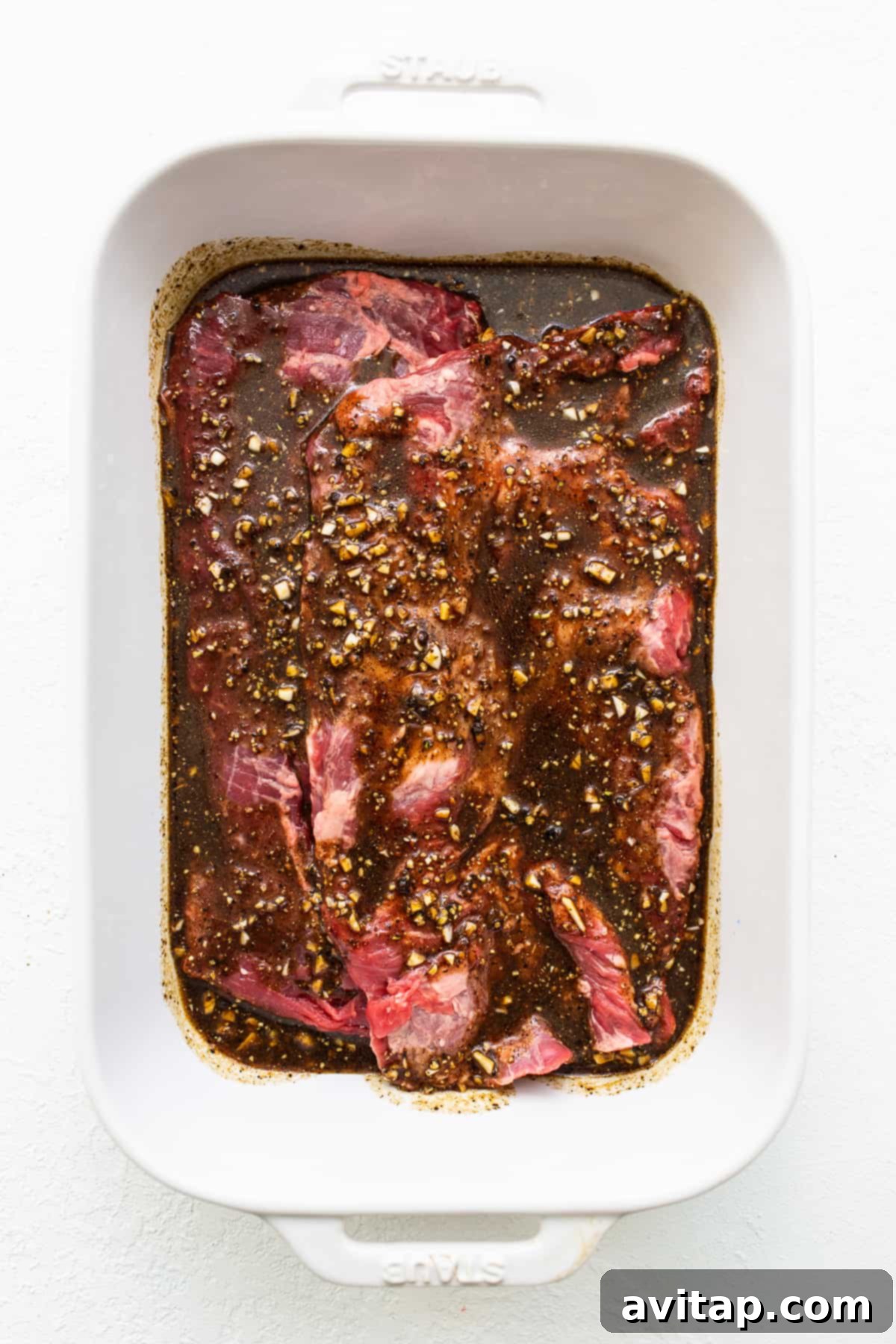 Skirt steak fully covered and marinating in a baking dish, ready for the refrigerator.