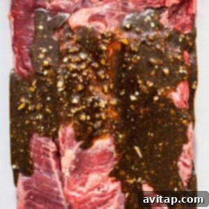 Skirt steak marinating in a dish, covered with the flavorful marinade.