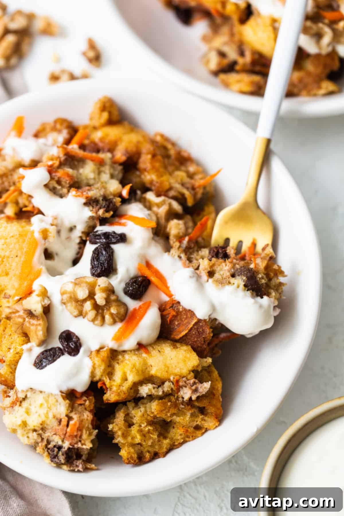 Carrot cake french toast casserole on a plate with a fork, ready to be enjoyed.