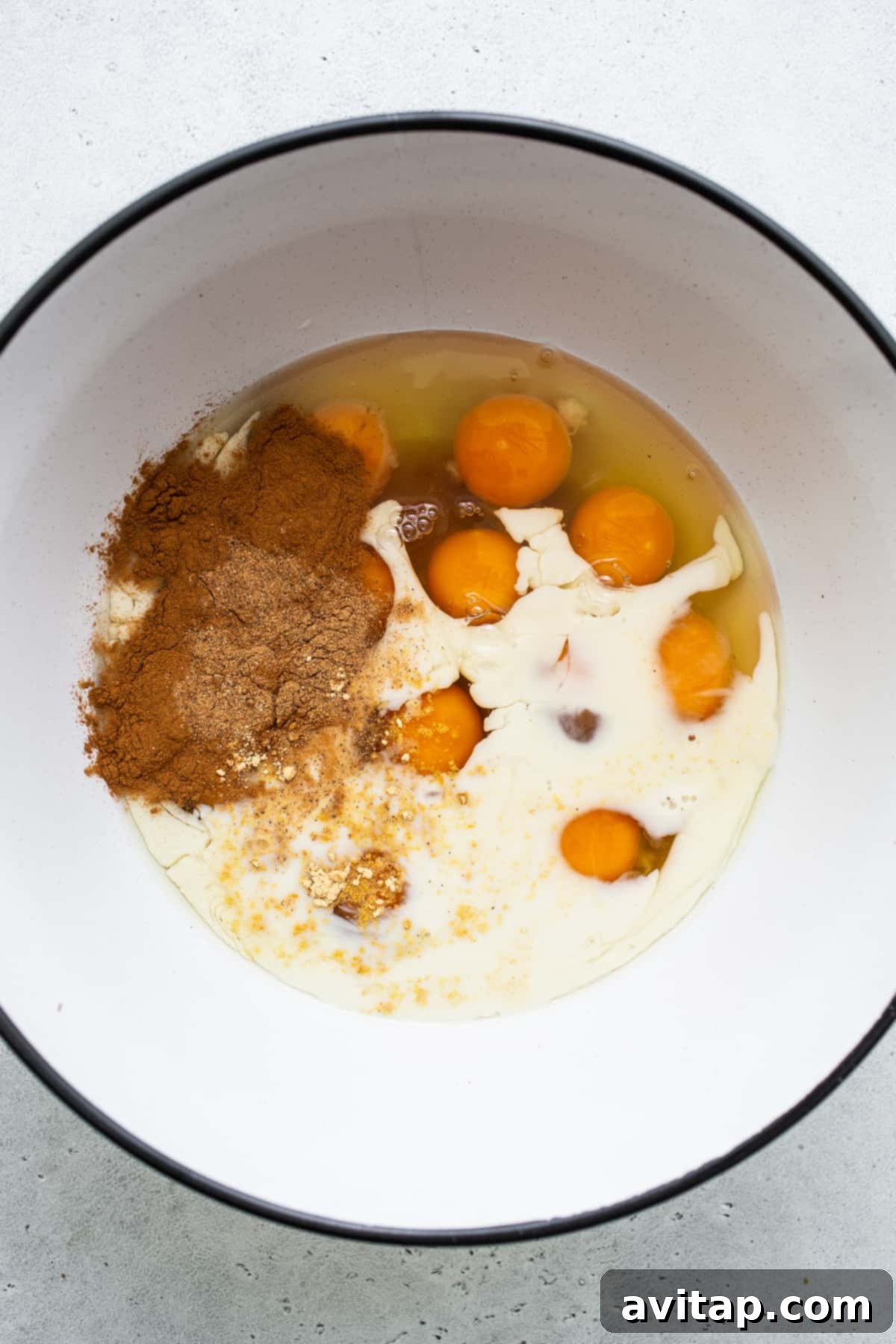 Eggs, milk, and warm spices whisked together in a bowl, forming the base for the carrot cake French toast casserole.