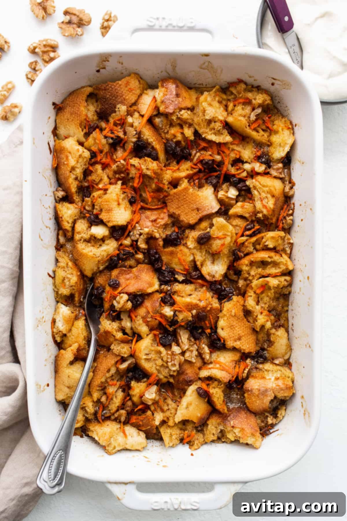 A spoon digging into a warm, inviting casserole dish of carrot cake french toast casserole.