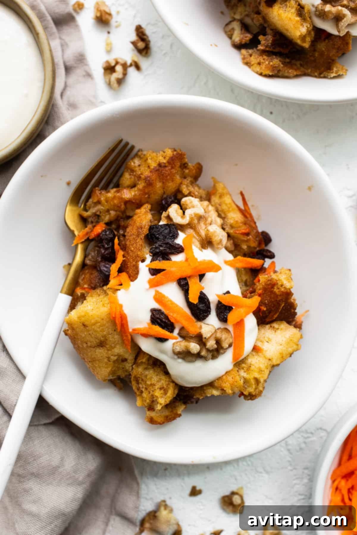 A single serving of carrot cake french toast casserole beautifully plated with a fork, ready for tasting.