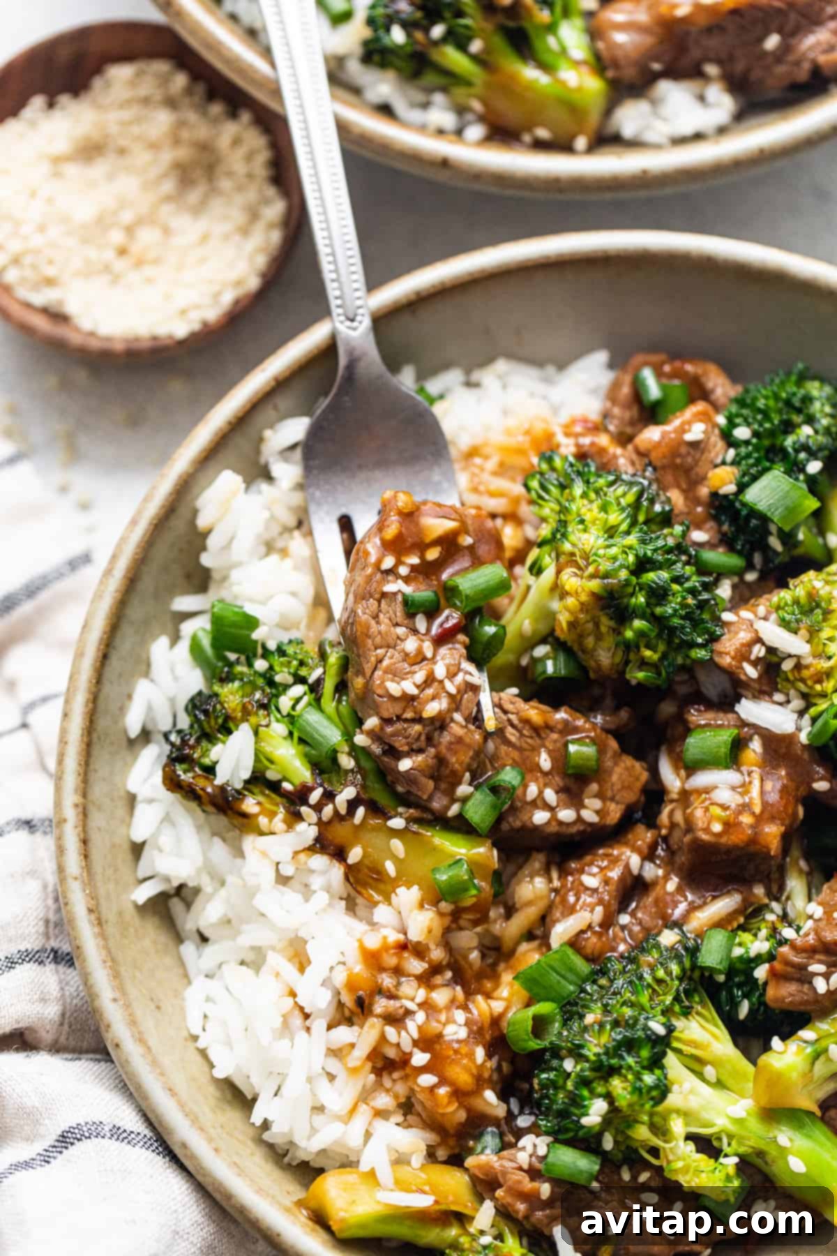 A vibrant bowl of homemade beef and broccoli stir-fry, garnished with sesame seeds.