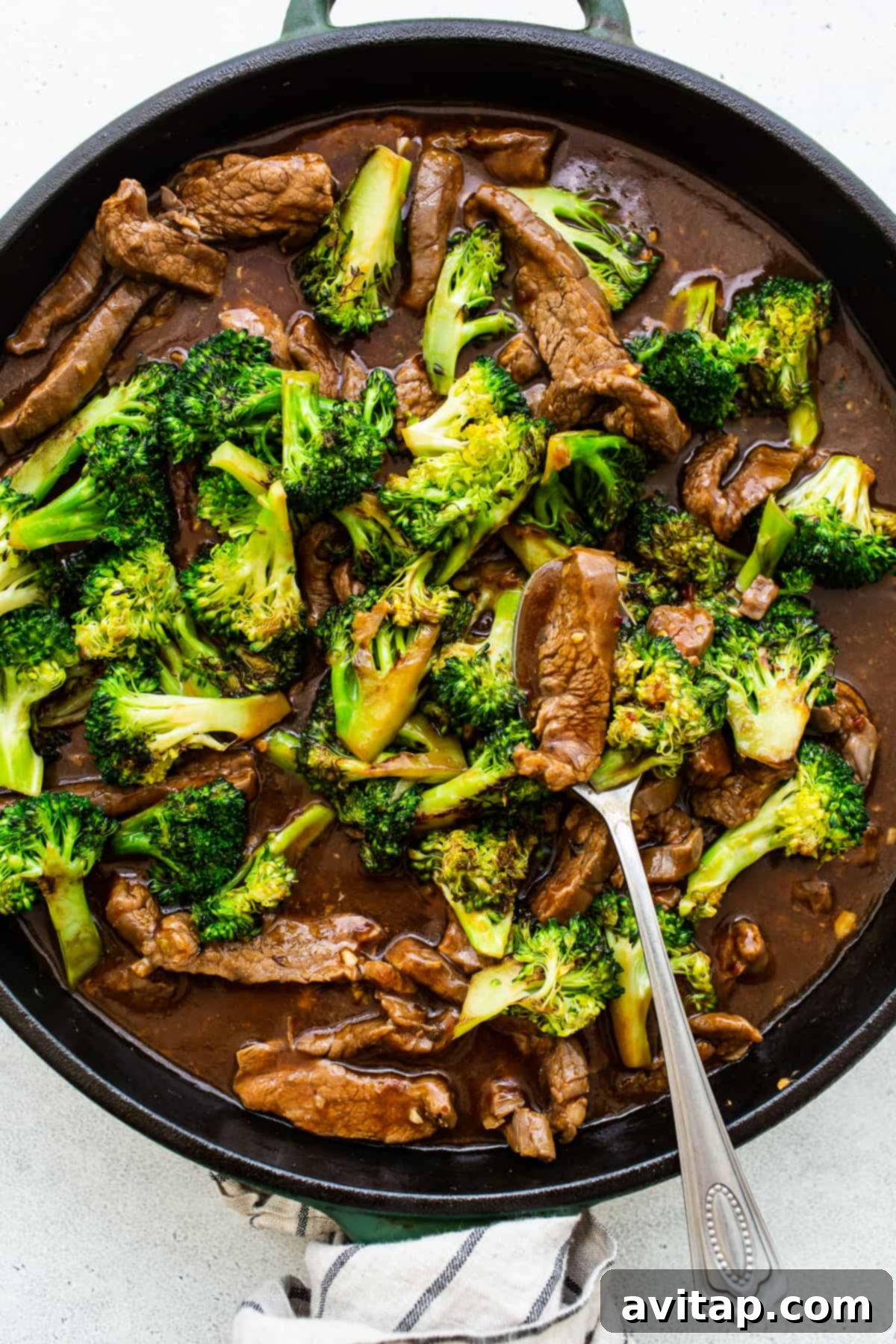 Beef and broccoli stir-frying in a large pan, coated in dark sauce.