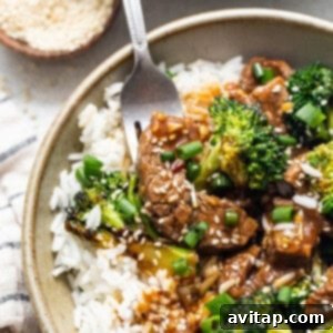 A bowl of beef and broccoli stir fry, garnished with sesame seeds.