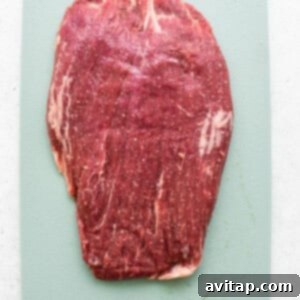 Tenderized beef flank steak on a cutting board.