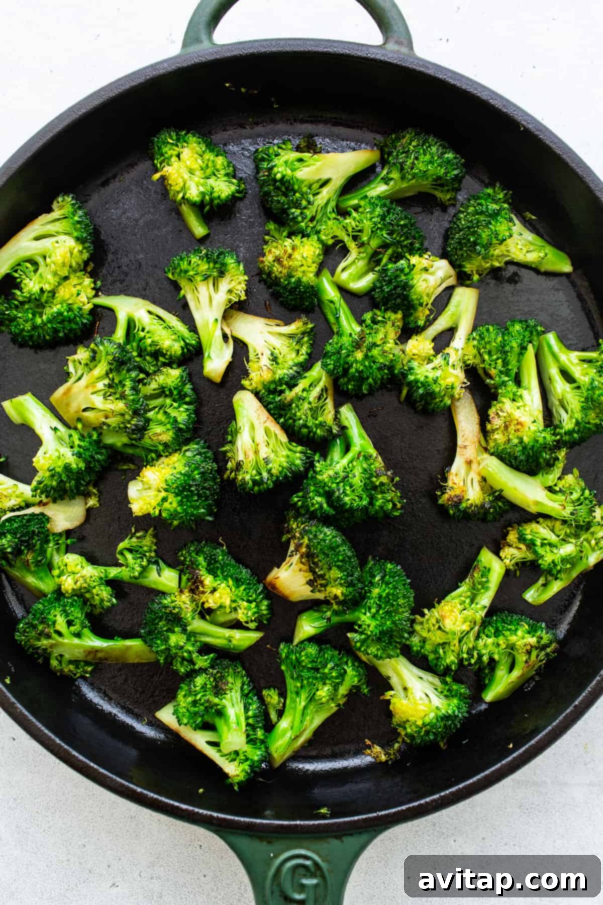 Crisp-tender sautéed broccoli florets in a cast iron pan.