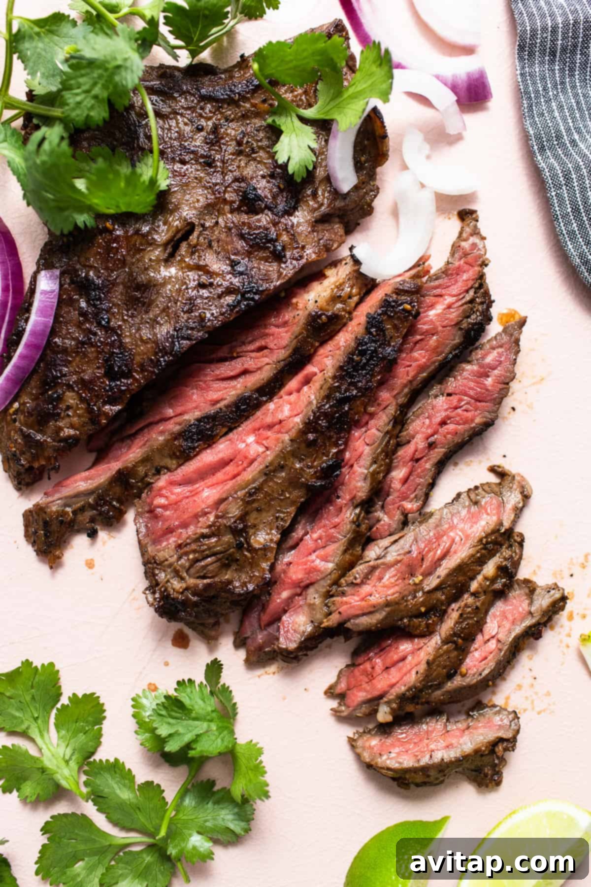 The Perfect Skirt Steak Recipe 2 Sliced skirt steak on a cutting board, garnished with fresh herbs.