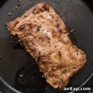 A piece of steak being cooked in a pan, searing beautifully.