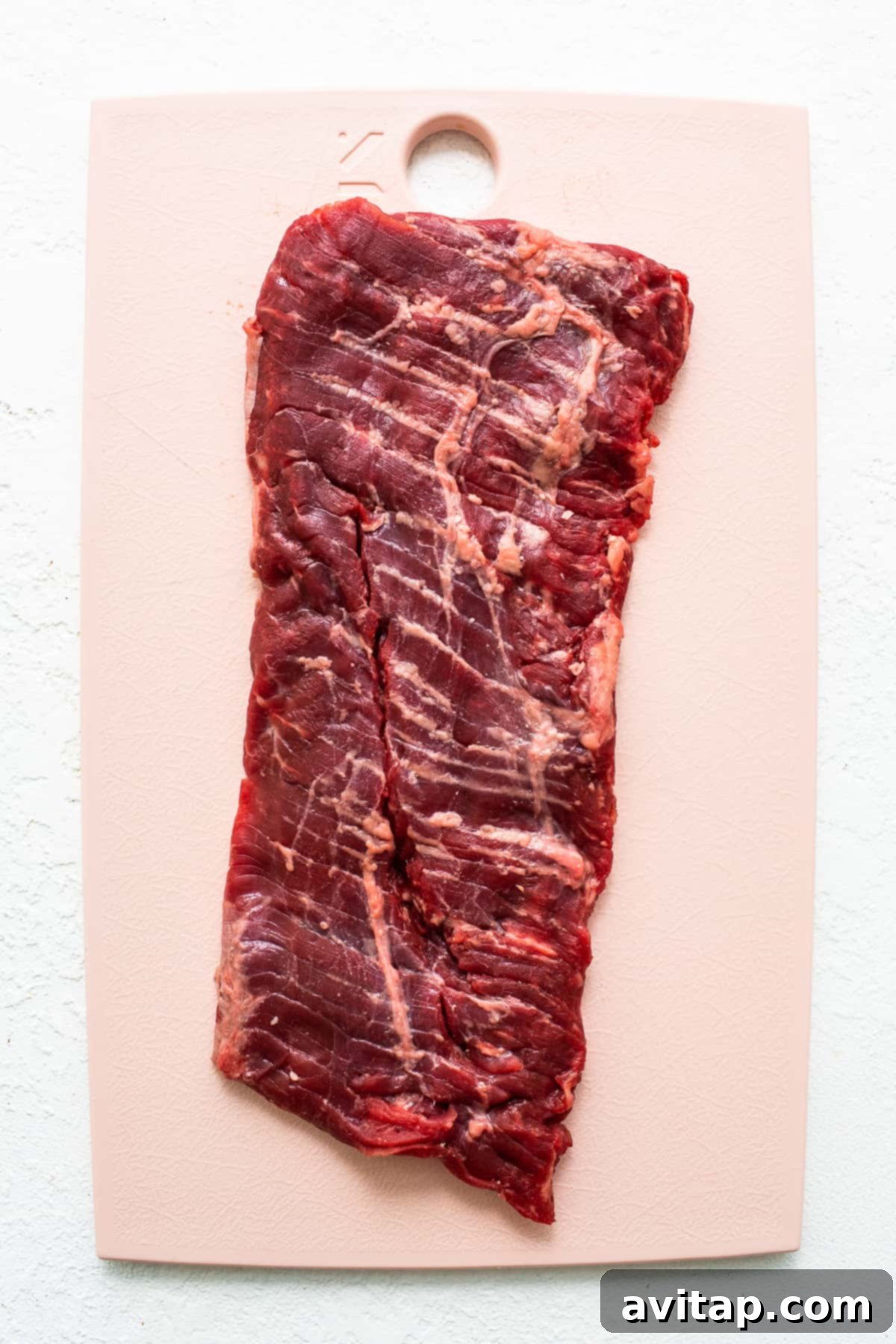 The Perfect Skirt Steak Recipe 3 Raw skirt steak on a cutting board, ready for preparation.