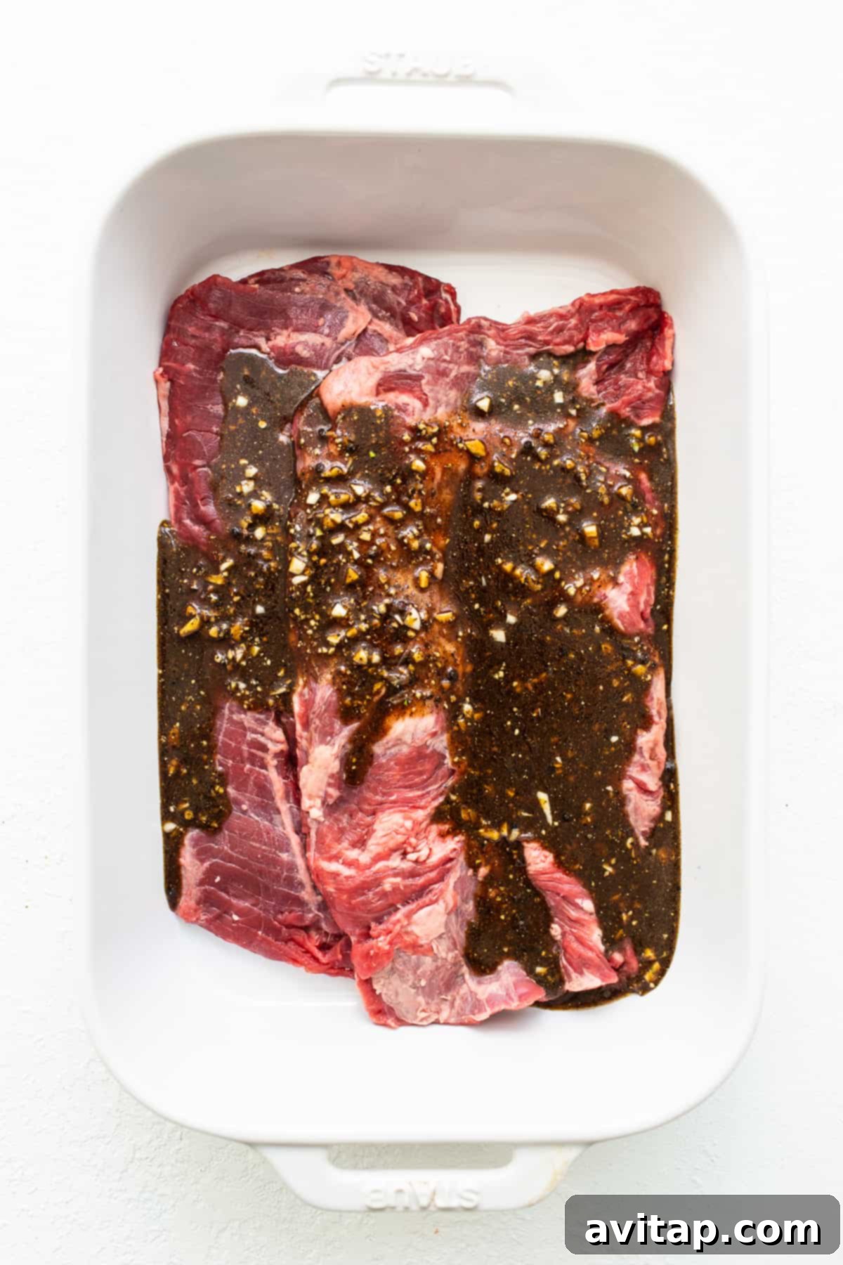The Perfect Skirt Steak Recipe 4 Skirt steak in a dish topped with marinade, ready for marination.