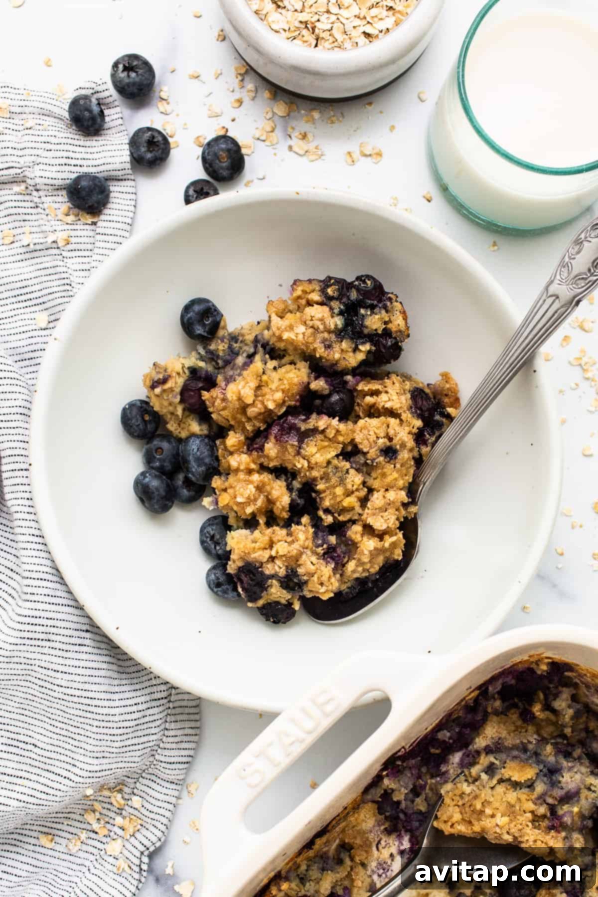 A bowl of blueberry muffin baked oatmeal with a spoon, highlighting its comforting texture.