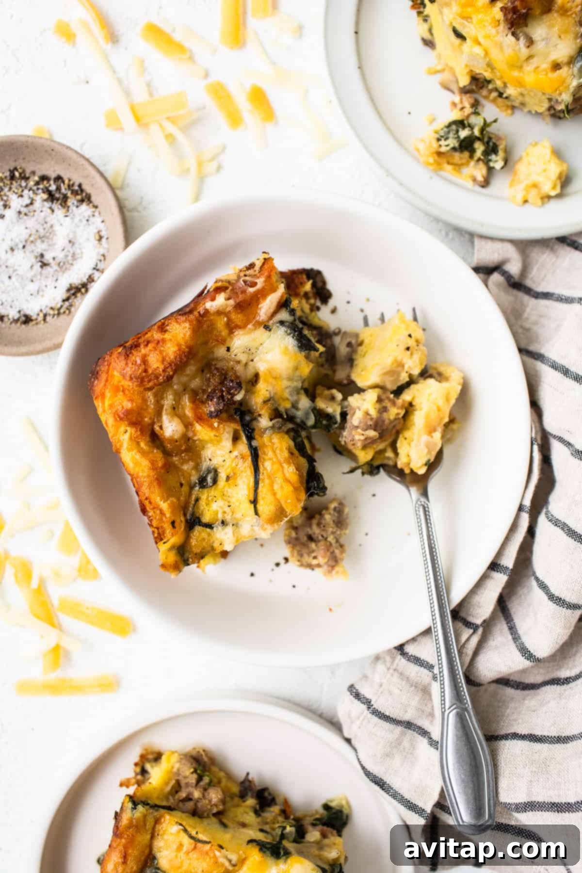 A perfectly cooked slice of breakfast strata served on a plate, showcasing its fluffy layers and golden crust.