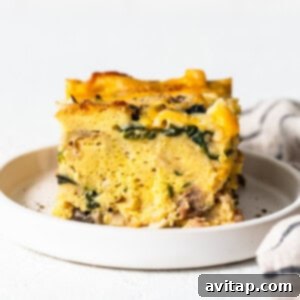 A mouth-watering slice of classic breakfast strata on a plate, showcasing the fluffy texture and savory fillings.