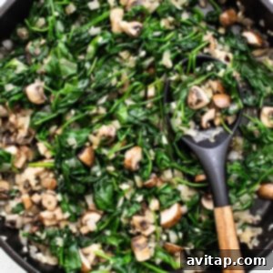 A skillet filled with vibrant sautéed spinach and mushrooms.