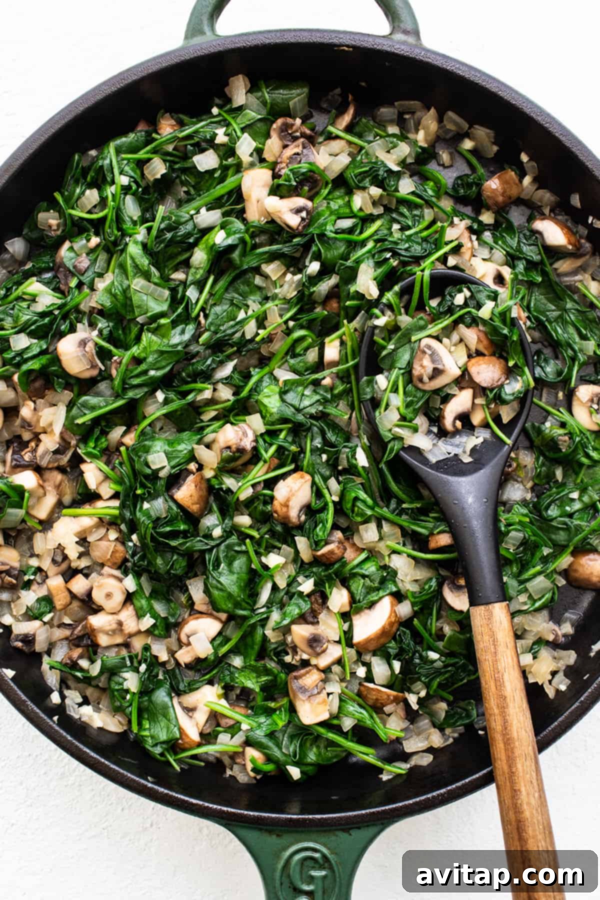 Close-up of vibrant sautéed spinach and mushrooms in a pan, ready for the breakfast strata.
