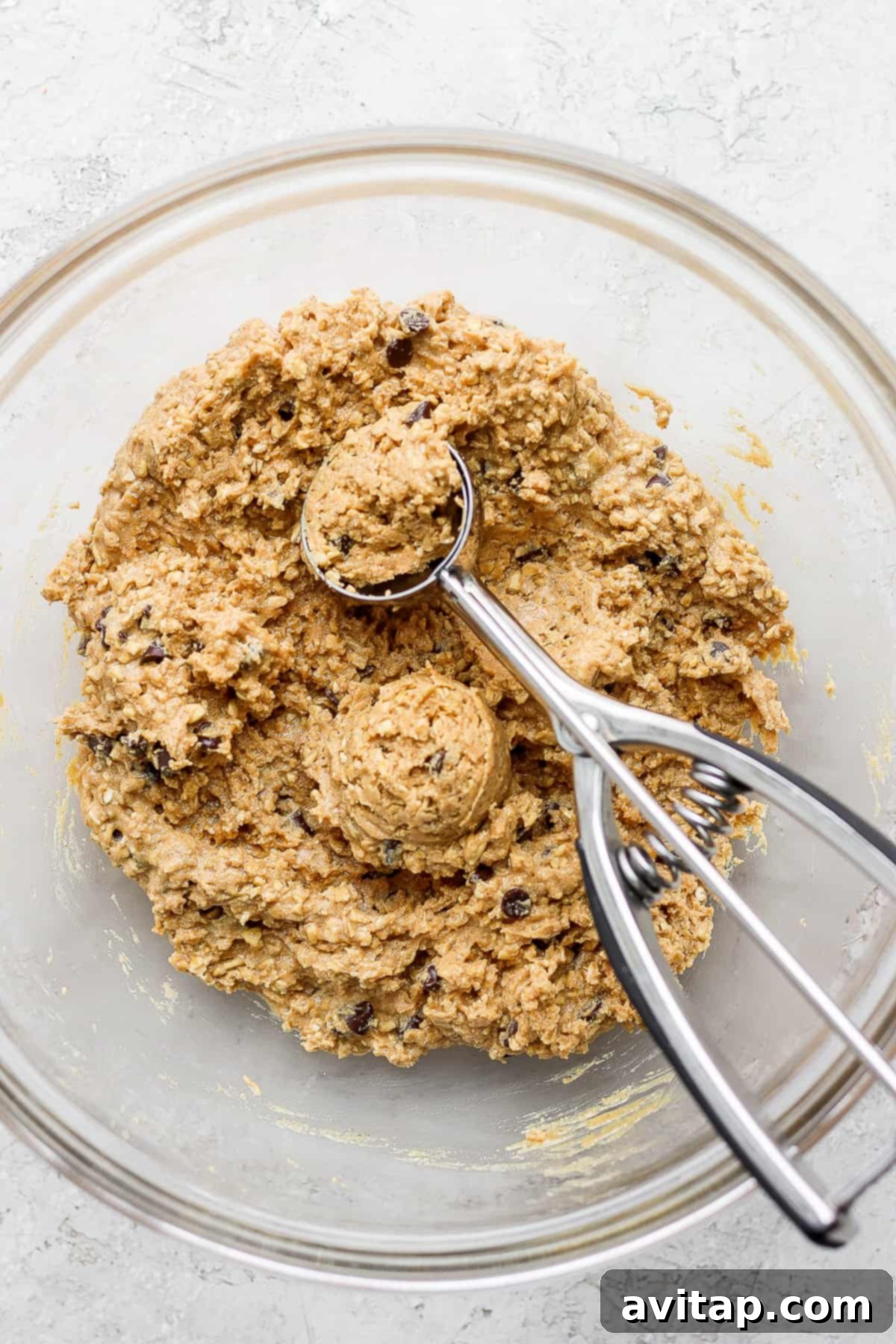 Mixed collagen cookie dough in a glass bowl, ready to be rolled into balls.