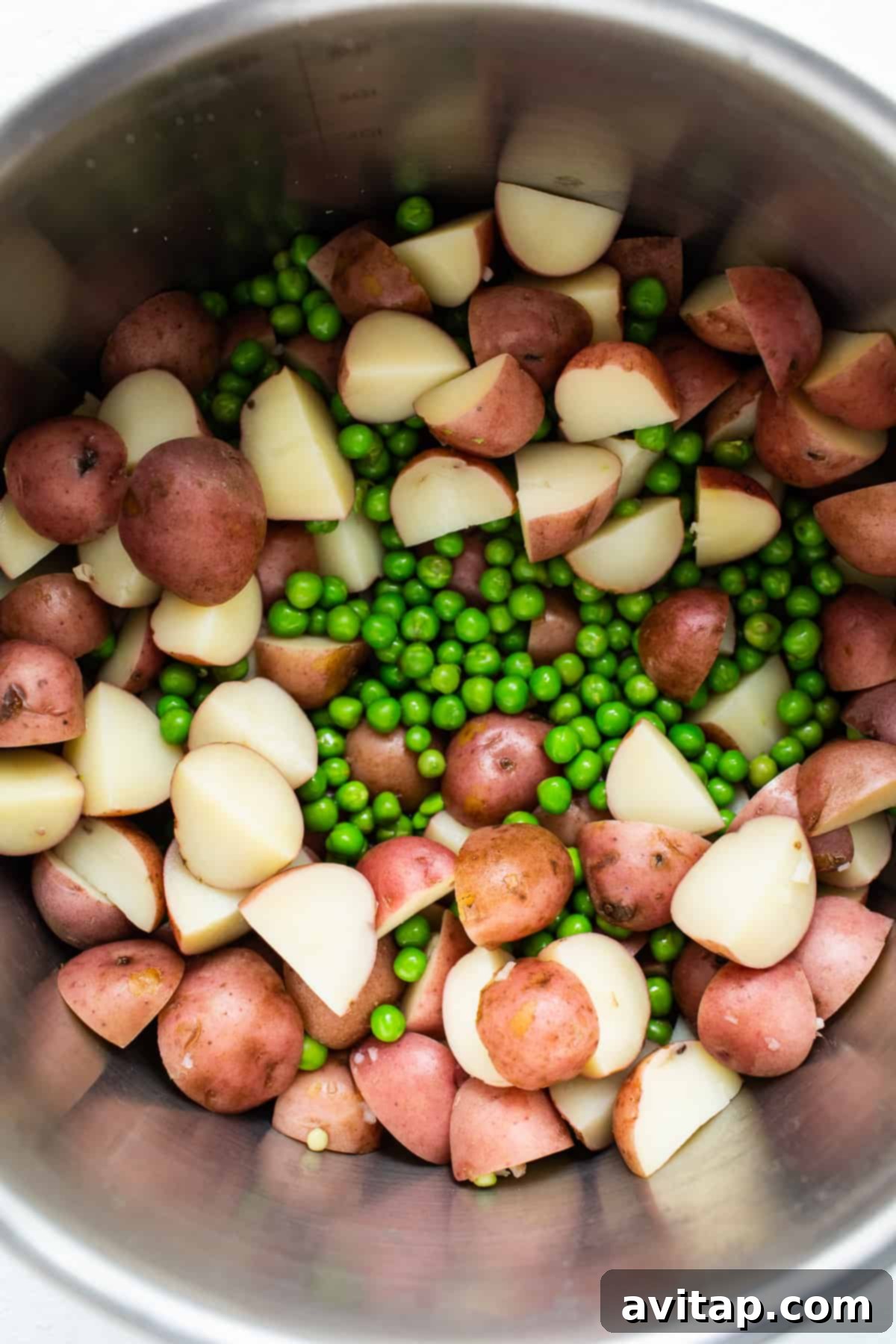 Red potatoes and english peas in a metal bowl.