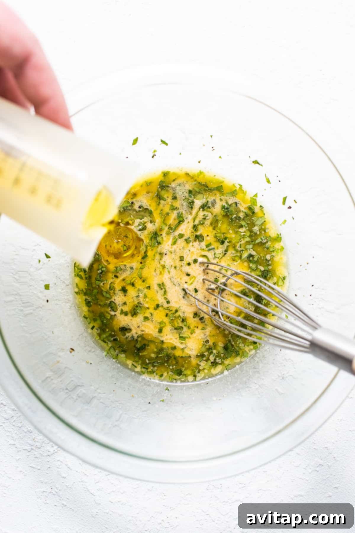 The herby hummus dressing being whisked in a glass bowl, showing its smooth consistency.