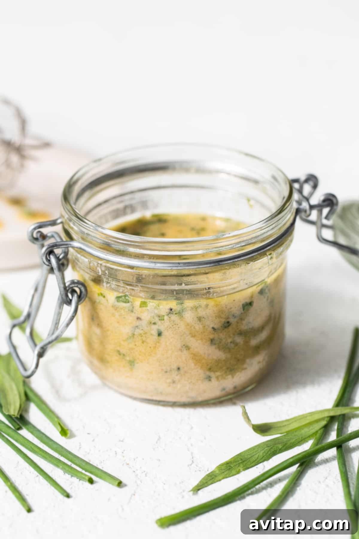Close-up of herby hummus dressing in a small glass jar, ready to be served.