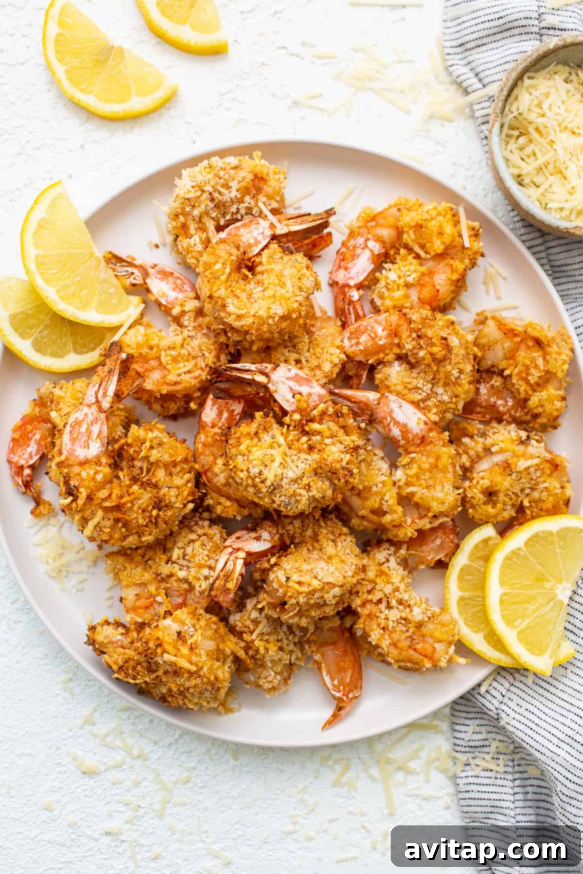 Crispy air fryer shrimp served on a plate with fresh lemon slices, ready to eat.