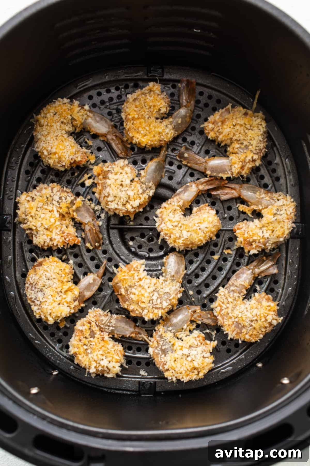 Multiple pieces of breaded shrimp neatly arranged in an air fryer basket, ready for cooking.