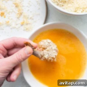 A person dipping a spoon into a bowl of soup.