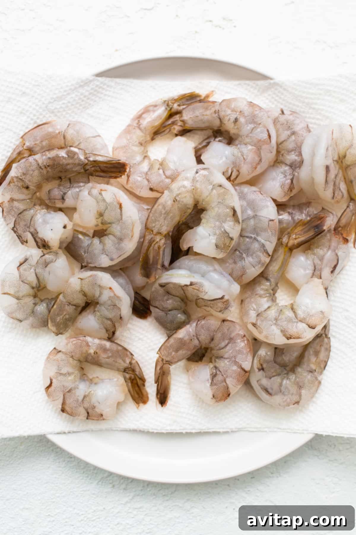 Fresh, raw, deveined shrimp laid out on a paper towel, ready for seasoning.