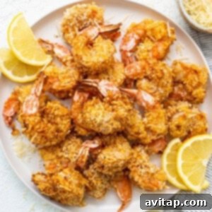 Air fryer shrimp on a plate with sliced lemons.