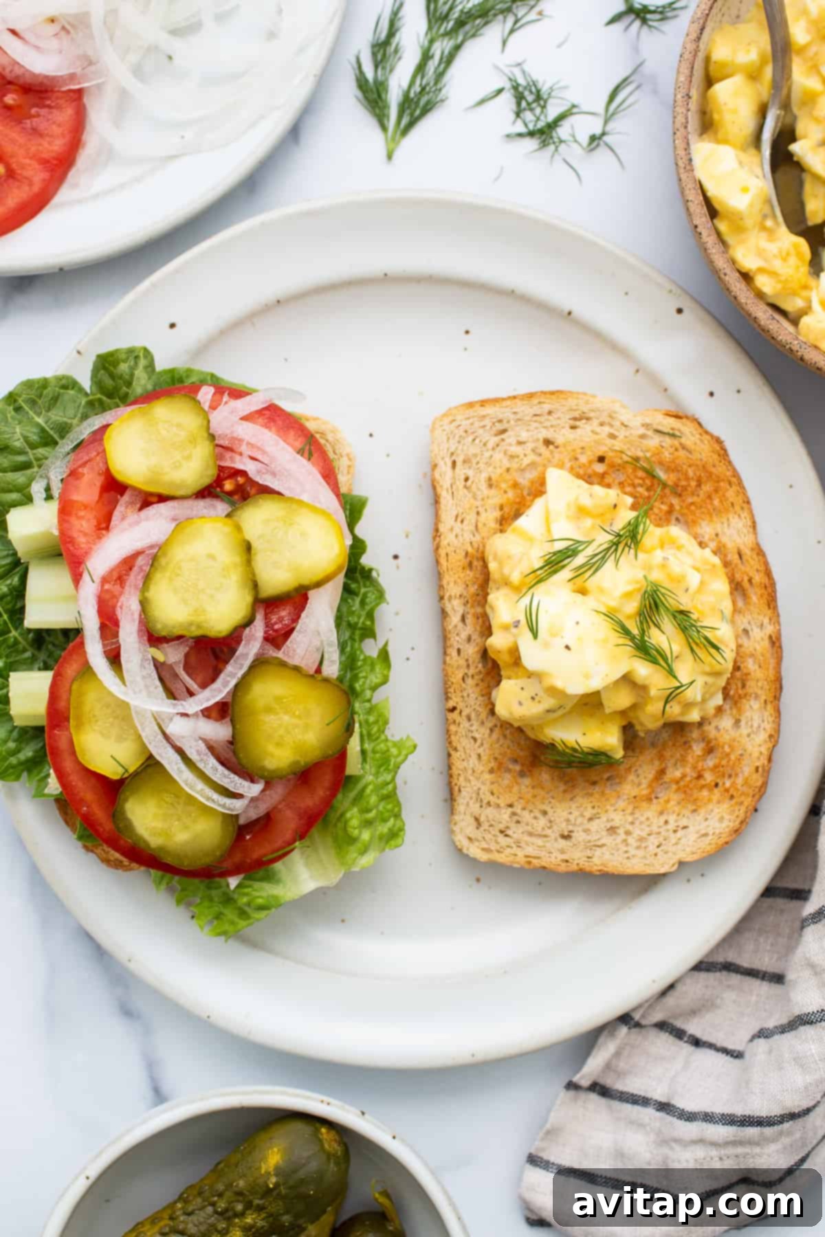 Classic Homemade Egg Salad Sandwich 3 Two halves of an egg salad sandwich artfully arranged on a plate, highlighting the creamy filling and fresh ingredients.