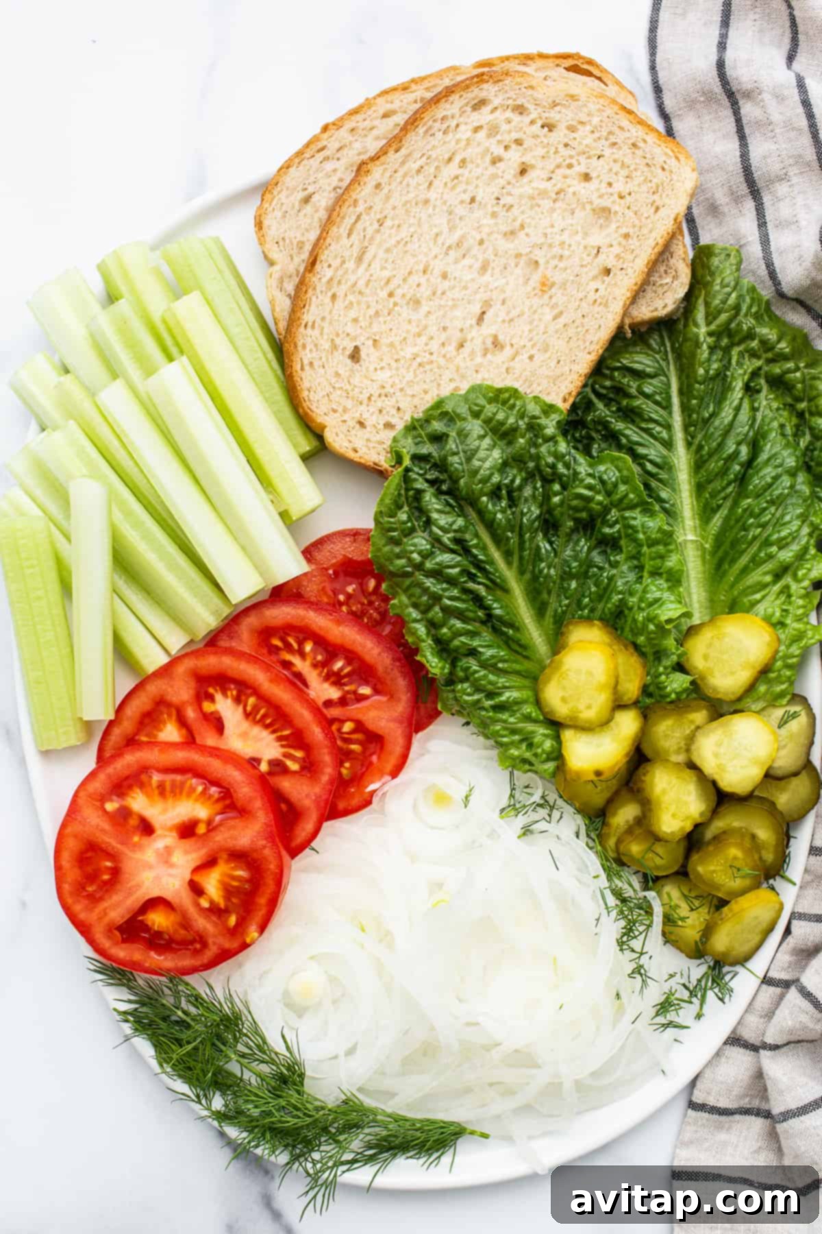 Classic Homemade Egg Salad Sandwich 4 A vibrant spread of fresh sandwich ingredients including lettuce, celery sticks, sliced pickles, juicy tomatoes, and onion slices, ready for assembly.