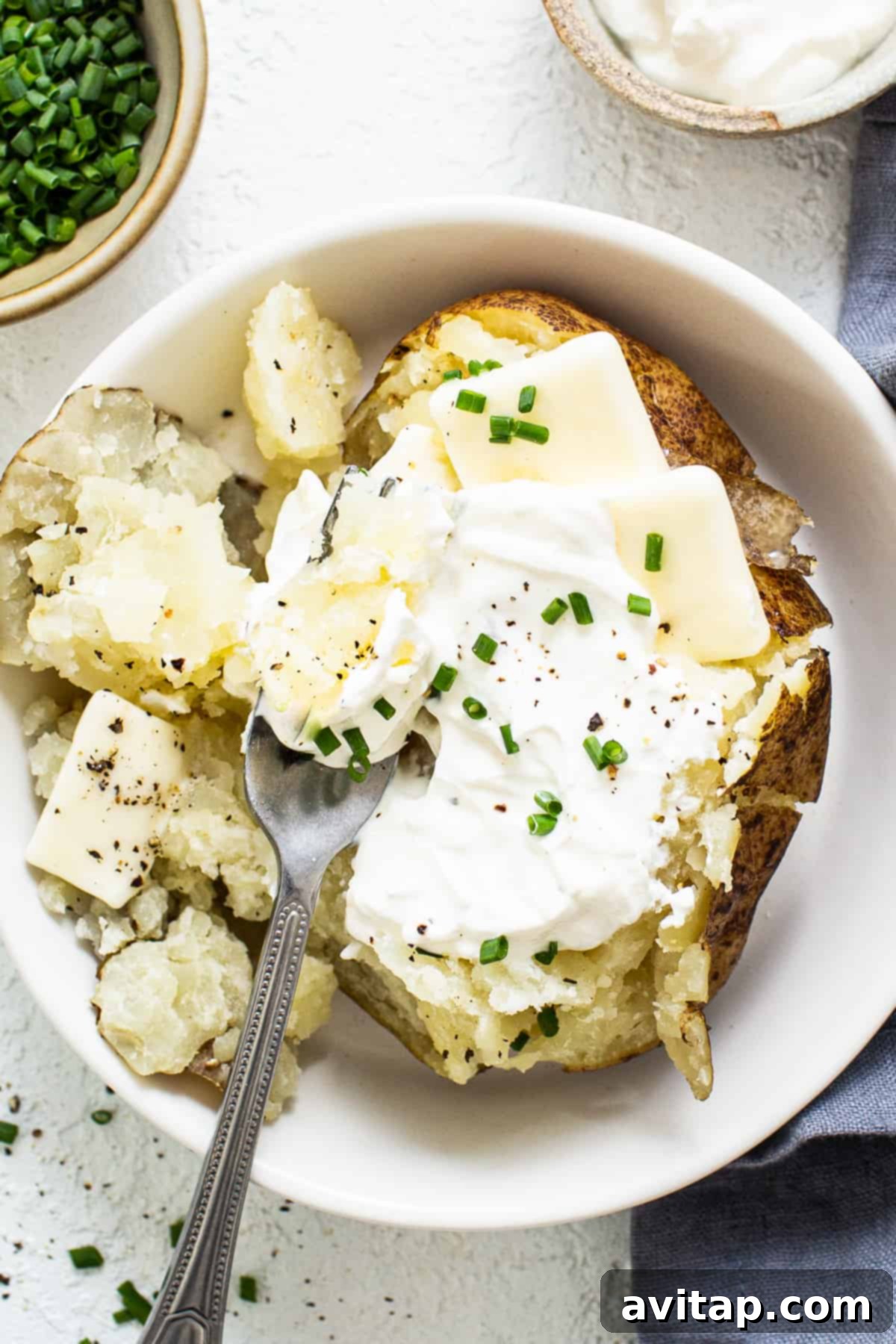 A perfectly cooked Instant Pot baked potato, split open and ready to be topped, resting in a rustic bowl.