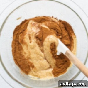 A bowl of cake batter being mixed with cinnamon for a dark swirl.