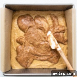The cinnamon layer being swirled into the coffee cake in the pan.