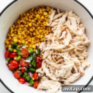 Fiesta Street Corn Chicken Salad 7 All the ingredients of the street corn chicken salad mixed together in a large white bowl, coated in dressing.