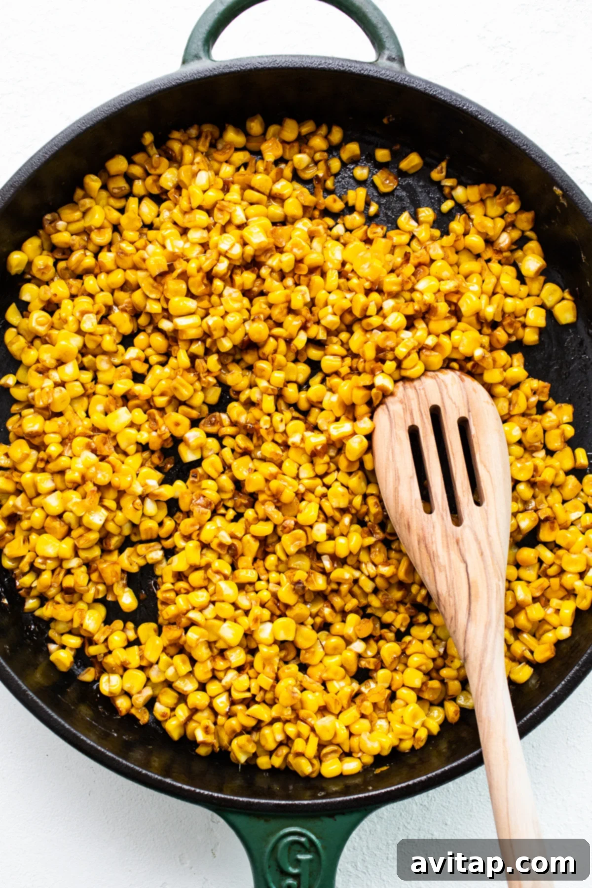 Roasting Corn for Maximum Flavor in Street Corn Chicken Salad Close-up of corn kernels sizzling and charring in a hot frying pan, creating a smoky aroma.