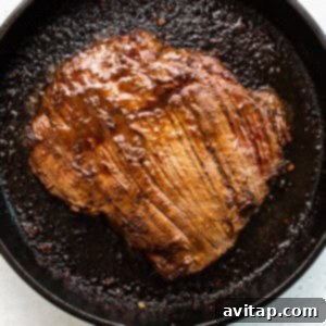 Ultimate Steak Fajita Marinade 7 A flank steak sizzling and cooking in a cast iron skillet, showing a beautiful sear.