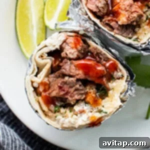 Ultimate Steak Fajita Marinade 2 Delicious steak burrito on a plate, filled with marinated fajita steak, veggies, and sauce.