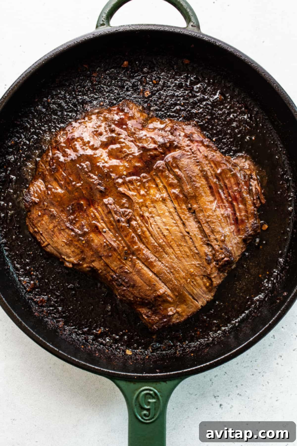 Flank Steak Searing in Cast Iron A flank steak sizzling beautifully in a hot cast iron pan, achieving a perfect sear.