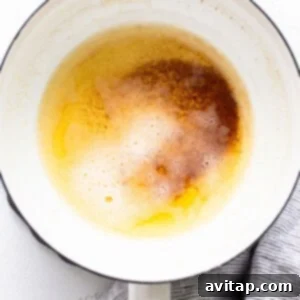 Unsalted butter melting and browning in a small saucepan, creating a nutty aroma.