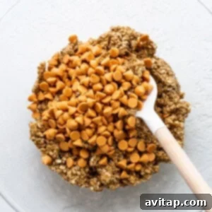 Fluffy cookie batter with visible butterscotch chips in a mixing bowl, ready for chilling.