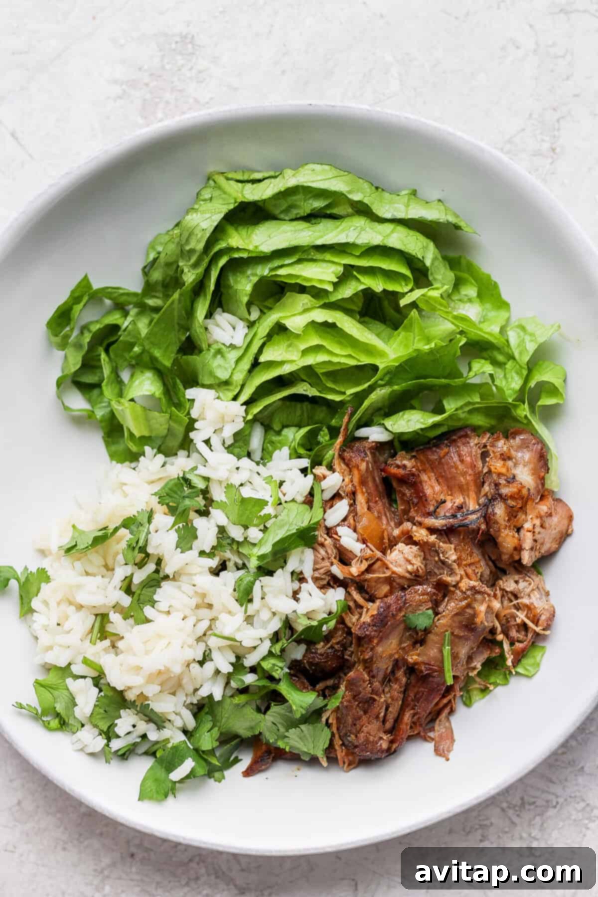 A white plate showcasing succulent slow cooker carnitas alongside fresh greens.