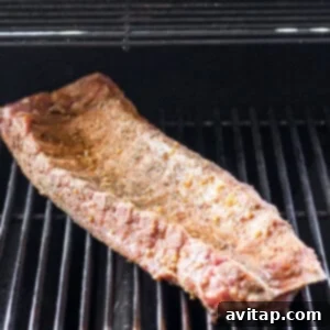 A rack of ribs cooking slowly over indirect heat on a grill.