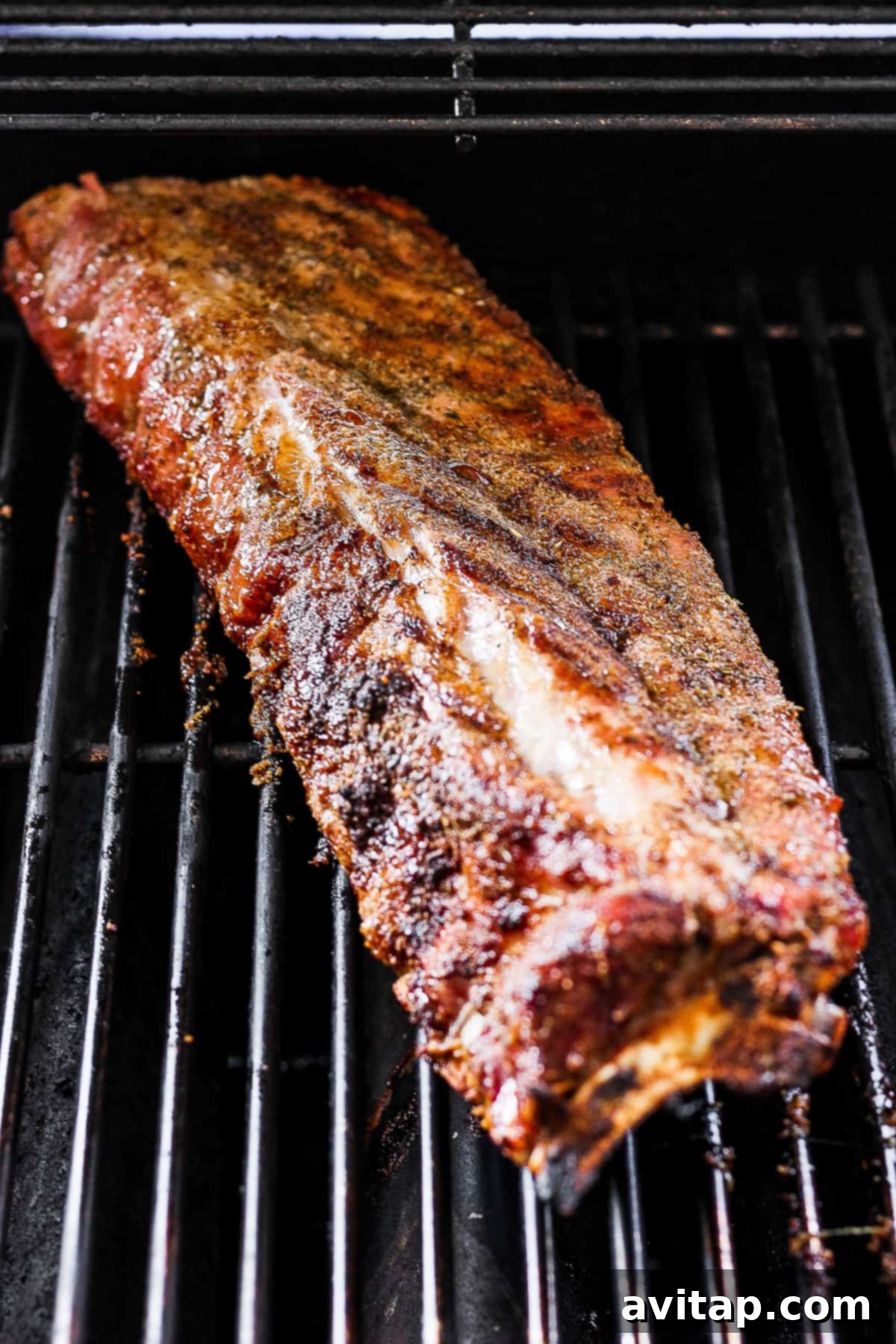 A rack of ribs slowly cooking on the grill, building a rich color and crust.