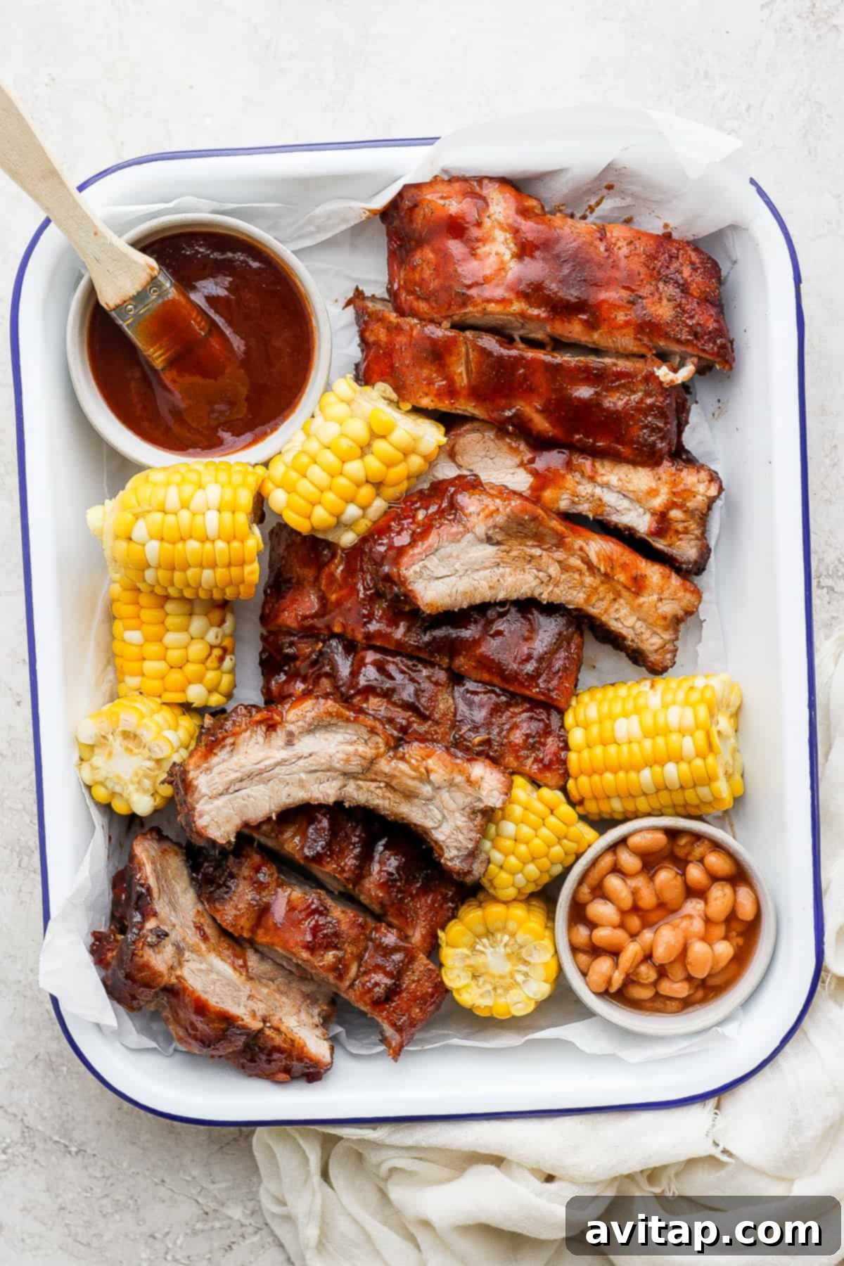 A serving tray laden with juicy grilled ribs and a bowl of BBQ sauce for dipping.