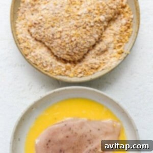 A chicken breast being coated in the cornflake and spice mixture.