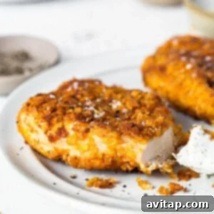 Cooked crispy chicken breast resting on a plate after frying.
