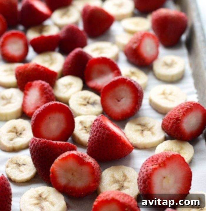 Frozen fruit slices on a parchment-lined baking sheet for smoothies.