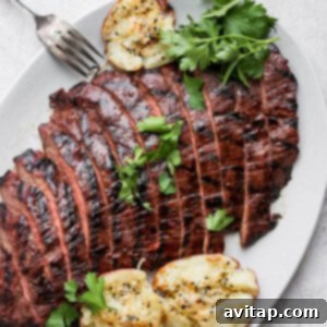 Grilled flank steak on a plate, perfectly cooked and ready to serve.