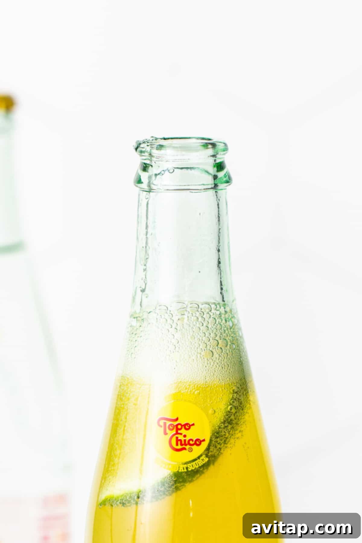 Classic Ranch Water with Lime Garnish A close-up of a Topo Chico bottle containing Ranch Water and a fresh lime slice.